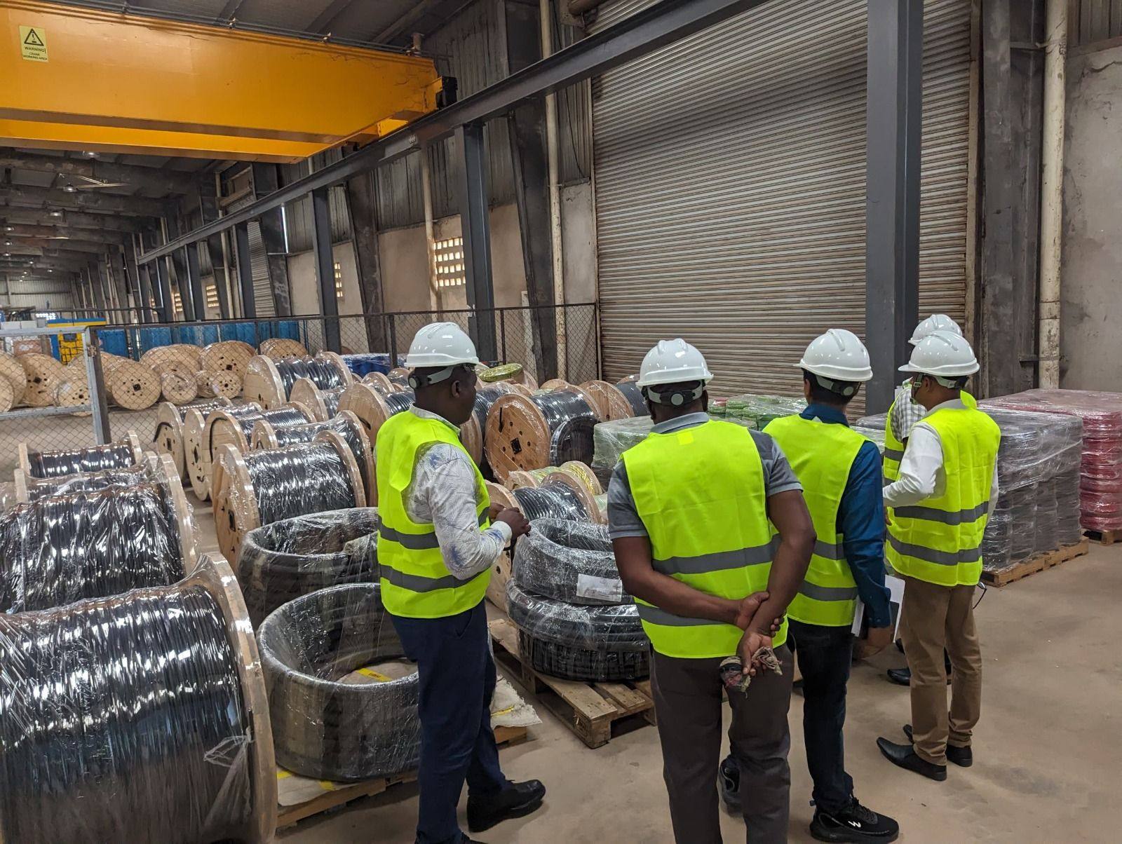 Engineers and client representatives inspecting cable drums in a warehouse